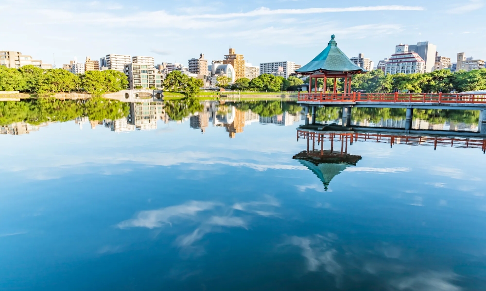 Hồ nước công viên Ohori trong xanh phản chiếu bầu trời và thành phố hiện đại Hakata.