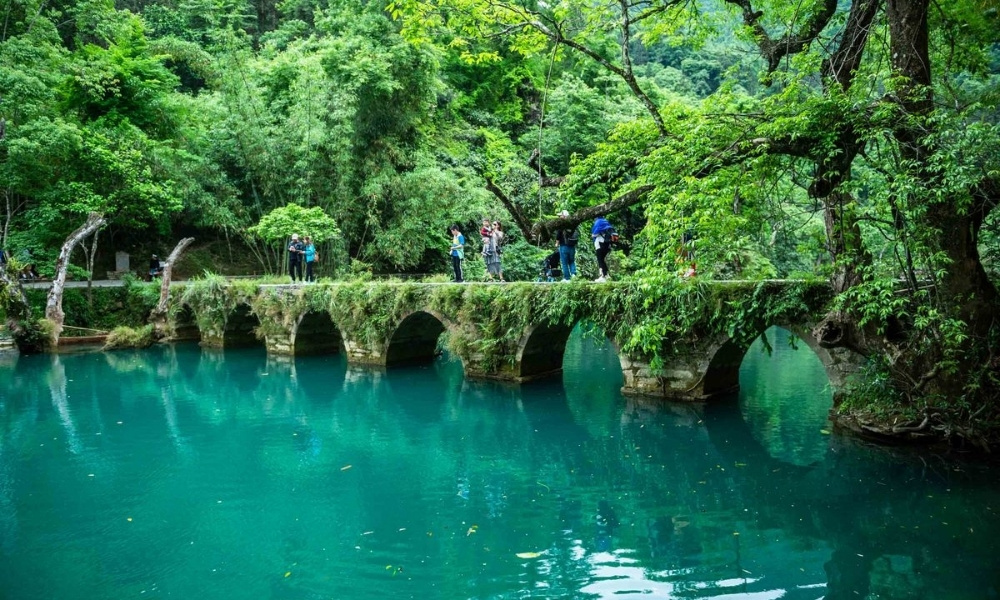 Cầu đá Tiểu Thất Khổng nằm e ấp giữa rừng xanh, soi bóng xuống dòng suối trong veo như dải lụa vắt ngang núi rừng Quý Châu